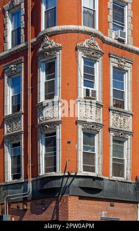 Kunstvoll verzierte Terrakotta-Spandrels und Fenster zieren dieses mittelhohe Apartment-Gebäude aus rotem Backstein in der Lower East Side von New York City. Stockfoto