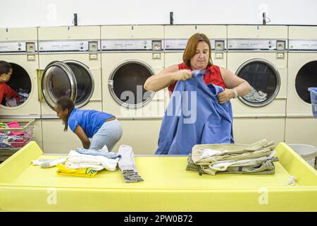 Virginia Roanoke Waschsalon innen Waschmaschinen münzbetrieben, spanisch-schwarze Afrikaner, Frau weibliche Falten Klamotten Kleidung Stockfoto