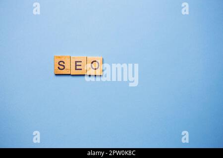 Hölzerne SEO-Buchstaben auf hellblauem Hintergrund Stockfoto