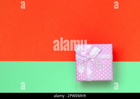 Kleine rosa Geschenkkarton liegen auf Textur Hintergrund der Mode pastell Farben Türkis und Rot Papier in minimalen Begriff. Stockfoto