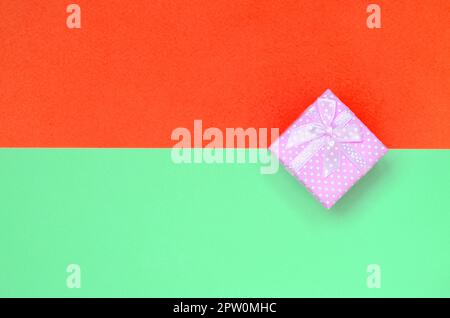Kleine rosa Geschenkkarton liegen auf Textur Hintergrund der Mode pastell Farben Türkis und Rot Papier in minimalen Begriff. Stockfoto