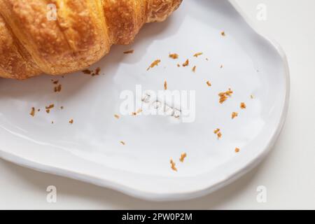 Weiße handgemachte Tonplatte mit frischem Croissant auf einem weißen Tabelle Stockfoto