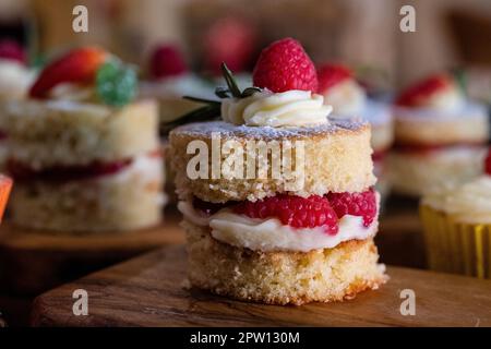 Wunderschöne Mini Victoria Schwämme mit frischen Himbeeren gefüllt mit Buttercreme und Obst Stockfoto