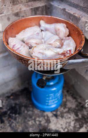 Spanische Mahlzeit im Freien. Frisch gebratene Hähnchenflügel auf einer Pfanne in einem Campinggasofen Stockfoto