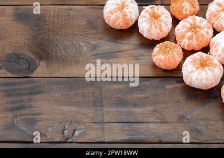 Viel frische Orangen Mandarinen liegen auf einem braunen Holz- Hintergrund. Flach mit Früchten in einem hölzernen Kasten Stockfoto