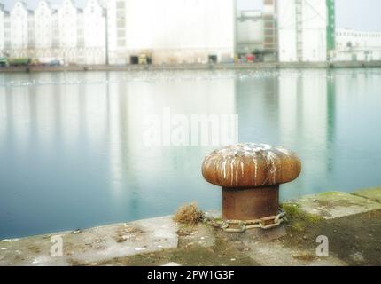 Rostige Anlegepfosten aus Gusseisen am Pier. Ein Pollenhafen an einem Hafen. Himmel- und Wasserhintergrund-Copyspace. Verankerungspunkt sichern, um ein Schiff zu verhindern Stockfoto