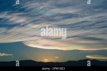Dünne, wispy Wolken erzeugen Regenbogenmuster von gestreutem Sonnenlicht. Optisches Phänomen auf Cirrostratus-Wolken. Stockfoto