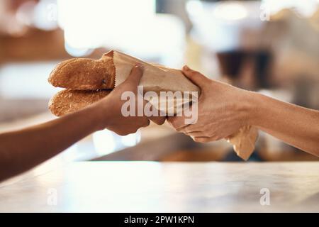 Kunde kauft Brot aus der Bäckerei, kauft Backwaren und kauft Lebensmittel in einem Geschäft. Hände von weiblichen Kunden und Angestellten, die Dienst tun, nehmen Stockfoto