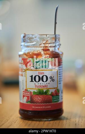 Posen, Polen - 22. April 2023: Polnische Erdbeermarmelade in einem geöffneten Glas auf einem Tisch. Stockfoto