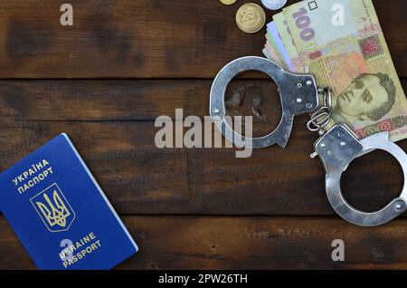 Ein Foto von einem ukrainischen ausländischer Reisepass, eine bestimmte Menge von ukrainischen Geld und Polizei Handschellen. Konzept der illegalen Ergebnis der Ukrainischen citiz Stockfoto
