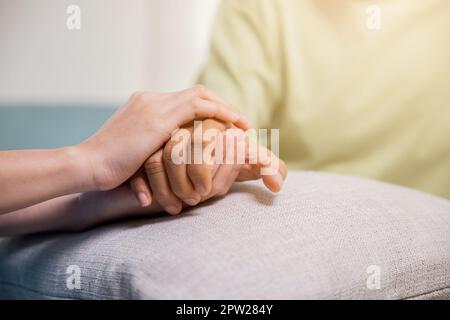 Internationaler Tag für ältere Menschen. Junge Frau, die ihrem älteren Mann zu Hause hilft, pflegende Krankenschwester, die Altenpflegeeinrichtungen hilft Stockfoto