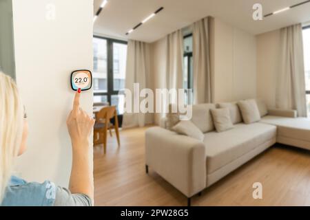 Frau, die ein Smartphone verwendet, um die Schnittstelle für die Konnektivität zu Hause zu steuern. Stockfoto