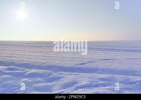 Ein weißes, schneebedecktes Stück Ackerland im Winter an einem sonnigen Tag Stockfoto