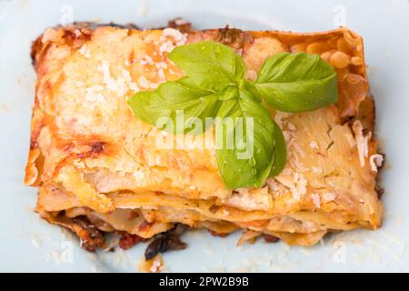 Lasagne mit Salat auf dunklem Holz Stockfoto