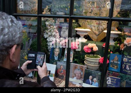 London, Großbritannien. 28. April 2023. Ein Mann fotografiert ein Schaufenster mit König Karl III. Vor seiner Krönung am 6. Mai 2023. Kredit: Kiki Streitberger/Alamy Live News Stockfoto