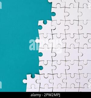 Fragment eines gefalteten weißen Puzzle auf dem Hintergrund einer blauen Kunststoff Oberfläche. Textur Foto mit Platz für Text kopieren Stockfoto