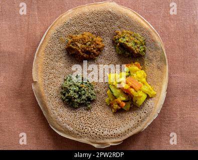 Injera mit Linsen und Gemüse, saure fermentierte Pfannkuchen-ähnliches Fladenbrot, ein Grundnahrungsmittel von Äthiopien und Eritrea Stockfoto