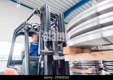 Gabelstaplerfahrer transportiert Material vom Lager zum Werk oder Industriegebiet Stockfoto