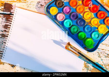 Satz Aquarellfarben, Pinsel und Papier auf Holzhintergrund. Stockfoto