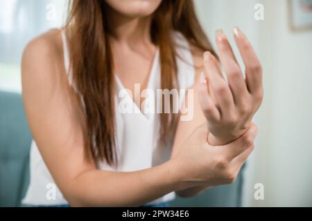 Nahaufnahme Hand. Asiatische junge Frau sitzt auf dem Sofa hält leiden ihr Handgelenk zu Hause, weibliche Handverletzung Gefühl Gelenkschmerzen, Durchführung einer Selbstmassage, Hea Stockfoto