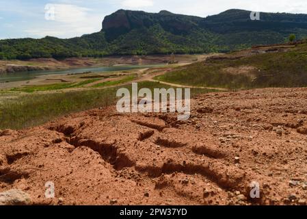 Vilanova de Sau, Spanien - 27. April 2023: Trockenes Land ist am Sau-Wasserreservoir zu sehen. Die Wasserreservoirs, eine der wichtigsten Wasserquellen der spanischen Region Katalonien und insbesondere der Stadt Barcelona, sind nach Angaben der katalanischen Wasserbehörde zu 6 % ausgelastet, während die Wasserreservoirs der Region zu 27 % ausgelastet sind. Die die lokale Regierung gezwungen hat, Maßnahmen gegen die Wasserknappheit zu ergreifen, da Spanien in eine Phase der chronischen Dürre eingetreten ist. Der rekordverdächtige Tiefstand hat die Stadt Sant Romà mit ihrem berühmten Glockenturm, der in den 60s Jahren überflutet wurde, wieder erobert Stockfoto