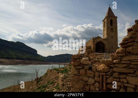 Vilanova de Sau, Spanien - 27. April 2023: Der freiliegende Glockenturm der Stadt ist am Sau Wasserreservoir zu sehen. Die Wasserreservoirs, eine der wichtigsten Wasserquellen der spanischen Region Katalonien und insbesondere der Stadt Barcelona, sind nach Angaben der katalanischen Wasserbehörde zu 6 % ausgelastet, während die Wasserreservoirs der Region zu 27 % ausgelastet sind. Die die lokale Regierung gezwungen hat, Maßnahmen gegen die Wasserknappheit zu ergreifen, da Spanien in eine Phase der chronischen Dürre eingetreten ist. Der rekordverdächtige Tiefstand hat die Stadt Sant Romà mit ihrem berühmten Glockenturm, der fl Stockfoto