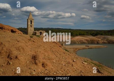 Vilanova de Sau, Spanien - 27. April 2023: Der freiliegende Glockenturm der Stadt ist am Sau Wasserreservoir zu sehen. Die Wasserreservoirs, eine der wichtigsten Wasserquellen der spanischen Region Katalonien und insbesondere der Stadt Barcelona, sind nach Angaben der katalanischen Wasserbehörde zu 6 % ausgelastet, während die Wasserreservoirs der Region zu 27 % ausgelastet sind. Die die lokale Regierung gezwungen hat, Maßnahmen gegen die Wasserknappheit zu ergreifen, da Spanien in eine Phase der chronischen Dürre eingetreten ist. Der rekordverdächtige Tiefstand hat die Stadt Sant Romà mit ihrem berühmten Glockenturm, der fl Stockfoto