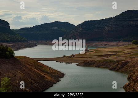 Vilanova de Sau, Spanien - 27. April 2023: Landschaftsblick am Sau-Wasserreservoir. Die Wasserreservoirs, eine der wichtigsten Wasserquellen der spanischen Region Katalonien und insbesondere der Stadt Barcelona, sind nach Angaben der katalanischen Wasserbehörde zu 6 % ausgelastet, während die Wasserreservoirs der Region zu 27 % ausgelastet sind. Die die lokale Regierung gezwungen hat, Maßnahmen gegen die Wasserknappheit zu ergreifen, da Spanien in eine Phase der chronischen Dürre eingetreten ist. Der rekordverdächtige Tiefstand hat die Stadt Sant Romà mit ihrem berühmten Glockenturm, der in den 60s Jahren überflutet wurde, wieder erobert Stockfoto