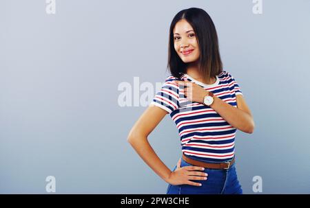 Das ist eine tolle Geschenkidee. Studiofoto einer attraktiven jungen Frau, die vor grauem Hintergrund auf den Kopierbereich zeigt. Stockfoto