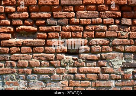 Horizontale wand Textur aus mehreren Zeilen der sehr alten Mauerwerk aus rotem Backstein. Erschüttert und beschädigt Mauer mit geknickte Ecken Stockfoto