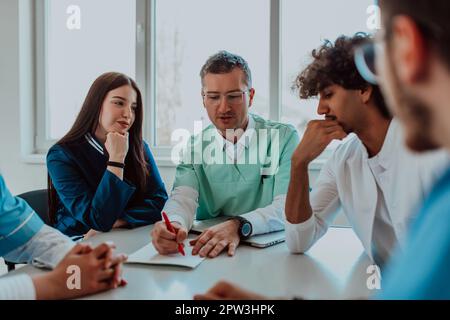 Eine Gruppe von multiethnischen medizinischen Fachkräften, darunter Ärzte, Chirurgen und Krankenschwestern, sind in einem Krankenhaus zusammengekommen, um die Patientenversorgung und zu diskutieren Stockfoto