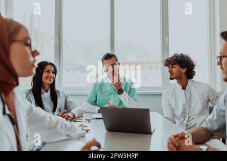 Eine Gruppe von multiethnischen medizinischen Fachkräften, darunter Ärzte, Chirurgen und Krankenschwestern, sind in einem Krankenhaus zusammengekommen, um die Patientenversorgung und zu diskutieren Stockfoto