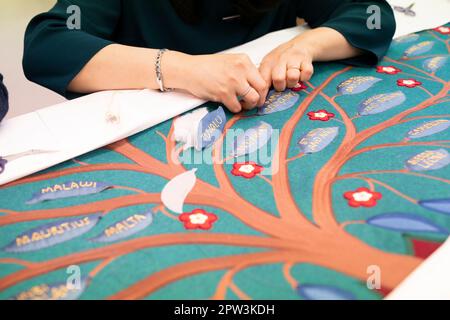 Stickereien arbeiten an einem Teil der Salbenleinwand während eines Besuchs von König Karl III. Und der Königin Consort zum Royal College of Needlework im Hampton Court Palace in East Molesey, Surrey, um den Fortschritt zu sehen und die Handwerker und Stickerinnen zu treffen, die an dem Projekt beteiligt waren. Die Salbenwand wird für den heiligsten Moment der Krönung am 6. Mai verwendet, vor der Amtseinführung und Krönung des Königs. Foto: Dienstag, 21. März 2023. Stockfoto