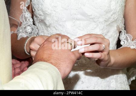 Die Hände Der Braut Und Des Zimmers Legen Hochzeitsringe. Stockfoto