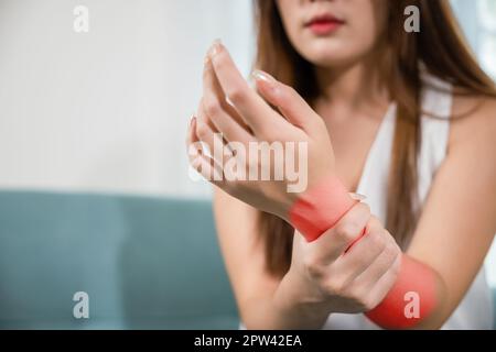 Nahaufnahme Hand. Asiatische Frau Hand Problem Verletzung Gefühl Gelenkschmerzen, junge Frau, die auf dem Sofa sitzt, leidet ihr Handgelenk zu Hause, führt Selbstmassen durch Stockfoto