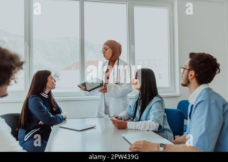 Eine Gruppe von multiethnischen medizinischen Fachkräften, darunter Ärzte, Chirurgen und Krankenschwestern, sind in einem Krankenhaus zusammengekommen, um die Patientenversorgung und zu diskutieren Stockfoto