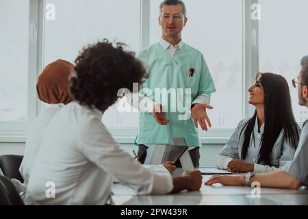 Eine Gruppe von multiethnischen medizinischen Fachkräften, darunter Ärzte, Chirurgen und Krankenschwestern, sind in einem Krankenhaus zusammengekommen, um die Patientenversorgung und zu diskutieren Stockfoto