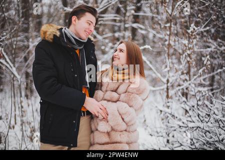 Foto eines wunderschönen jungen Teenager-Paares, das im kalten Winter Zeit miteinander verbringt, ein Typ, der ein Mädchen umarmt, um sie an einem frostigen Tag warm zu halten. Romantisches Date Stockfoto