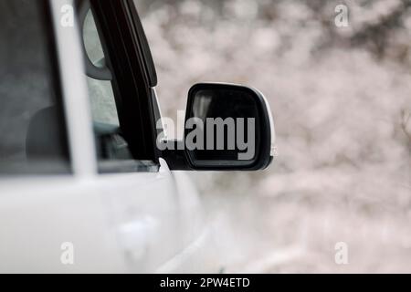 Weicher Fokus des weißen Fahrzeugs mit Flügelspiegel, der im Winter in schneebedeckter Landschaft geparkt ist Stockfoto