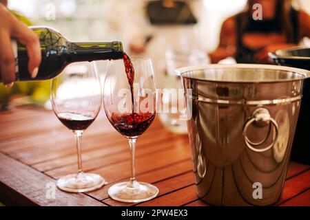 Gläser mit verschiedenen Weinsorten und menschlichen Händen, die Weingläser im Hintergrund halten. Degustationswein Stockfoto