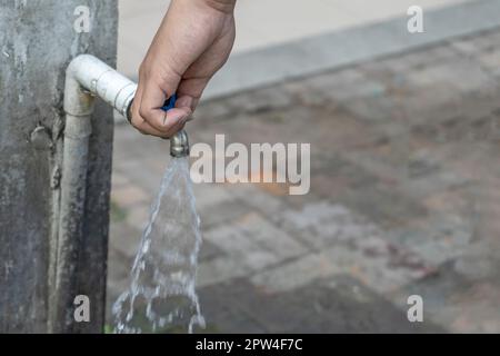 Alter Wasserhahn und Hand sind offenes Wasser. Stockfoto