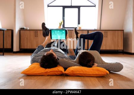 Mann und Frau, die sich auf der Social-Networking-Seite unterhalten. Frau, die sich Videos auf einem digitalen Tablet ansieht. Ein Paar verbringt Zeit miteinander Stockfoto