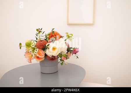 Glasvase mit Blumenstrauß auf dem Tisch in einem gemütlichen Zimmer. Platz für Text Stockfoto