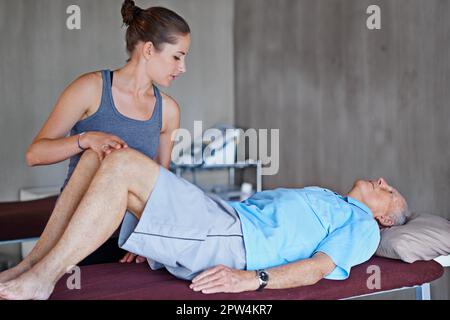 Die Wiederherstellung ist ein langer Prozess. Ein alter Mann, der eine Physiotherapie-Sitzung hat Stockfoto