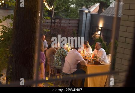 Viele Leute jubeln und zeigen einander ihre Champagnergläser voller Sekt, während sie eine Hochzeitsfeier im Freien auf einem genießen Stockfoto