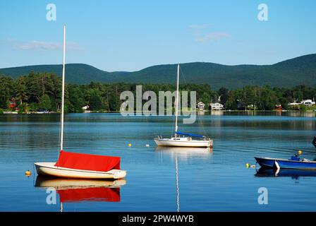 Kleine Segelboote und andere Wassersportboote sitzen auf einem ruhigen See und Teich in einem Bergtal Stockfoto