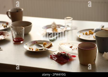 Nach dem Essen schmutzige Teller mit Löffeln und Gabeln auf dem Tisch leeren. Konzept für Bankettende. Ungewaschene Gerichte, die zur Reinigung bereit sind Stockfoto