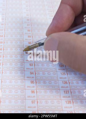 Der Kandidat hält einen Kugelschreiber während des Multiple-Choice-Tests. Prüfungskonzept Stockfoto