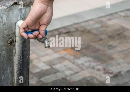 Alter Wasserhahn und Hand sind offenes Wasser. Stockfoto