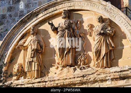 Relief auf der Rückseite des Haupttors, in dem die Schutzheiligen Maltas dargestellt werden: St. Paul im Zentrum mit St. Publius und St. Agatha an seiner Seite - Mdina Stockfoto